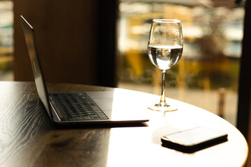 workplace, a glass of water, a laptop and a phone on the table