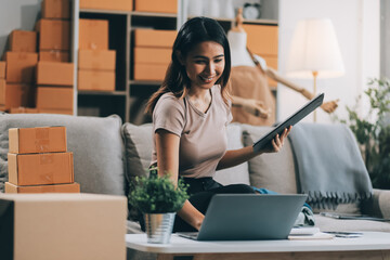 Asian SME business women use laptop computer checking customer order online shipping boxes at home....