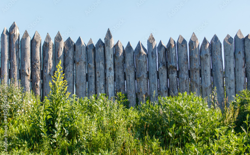 Wall mural wooden log fence against the sky