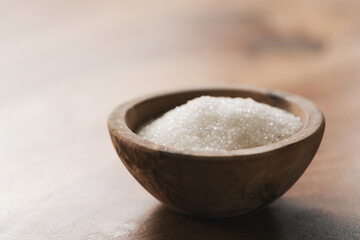 White sugar in wood bowl on table