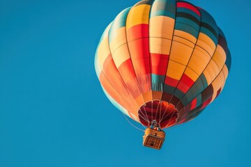 Fototapeta premium A close-up of a brightly patterned hot air balloon ascending into a clear blue sky, with the intricate basket and ropes visible in de