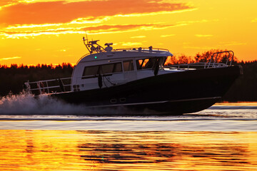 A river yacht, a speedboat, is sailing fast along the river at sunset. Evening rest on the water,...