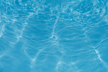Blue water with ripples on the surface. Defocus blurred transparent blue colored clear calm water surface texture with splashes and bubbles. Water waves with shining pattern texture background.