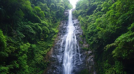 Stunning waterfall cascading down a rocky cliff surrounded by lush green forests, offering a peaceful and natural travel destination