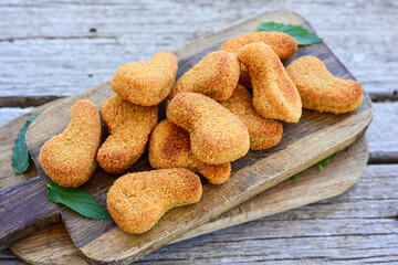 
 Crispy oven baked  chicken nuggets and ketchup. Breaded chicken fillets  with chilly peppers and fresh basi on wooden rustic background