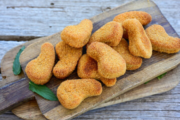 
 Crispy oven baked  chicken nuggets and ketchup. Breaded chicken fillets  with chilly peppers and fresh basi on wooden rustic background