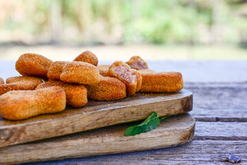 
 Crispy oven baked  chicken nuggets and ketchup. Breaded chicken fillets  with chilly peppers and fresh basi on wooden rustic background