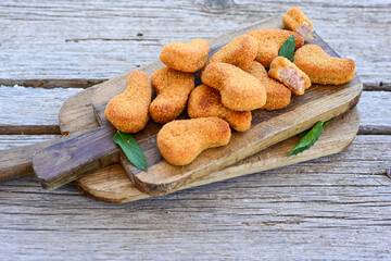 
 Crispy oven baked  chicken nuggets and ketchup. Breaded chicken fillets  with chilly peppers and fresh basi on wooden rustic background