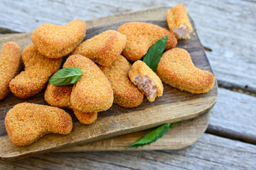 
 Crispy oven baked  chicken nuggets and ketchup. Breaded chicken fillets  with chilly peppers and fresh basi on wooden rustic background