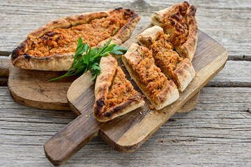  Traditional Turkish cuisine. Baked Pide dish with chicken ,  cheese and  herbs on  wooden background.  Turkish pizza pide