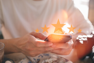 Customer service experience and satisfaction survey concept Close up of man customer sitting in cafe or restaurant giving a five star rating on smartphone. Review, Service rating, satisfaction