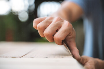 Close-up of a hand sanding a wooden surface with a block, focusing on craftsmanship and woodworking skills.