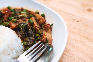 Close-up of a plate of rice with stir-fried century egg, pork, and basil, served with a fork.