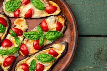 Italian mini pizza . Aubergine (eggplant ) with mozzarella cheese and basil . On rustic background