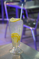 a tall glass filled with a refreshing lemon drink, garnished with a lemon wedge and a straw