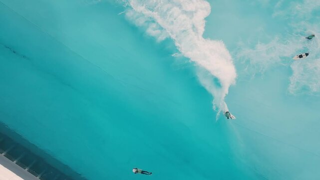 Surfing in the pool. Top down aerial view of the surfers riding wave in the pool