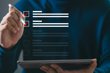 Hand holding stylus checks items on digital checklist displayed on tablet screen, concept of productivity and task management.