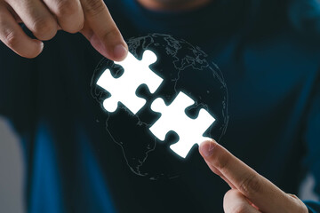 Hands holding pieces of a glowing puzzle, symbolizing connection and teamwork against a dark...