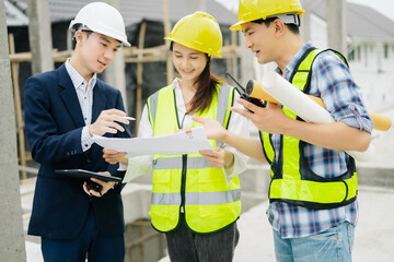 Contractor and architect looking at plan, tablet, laptop and talking about working on big project.