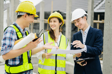 Contractor and architect looking at plan, tablet, laptop and talking about working on big project.