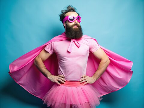 A bearded man wears a humorous pink tutu, oversized sunglasses, and a superhero cape, showcasing a playful and