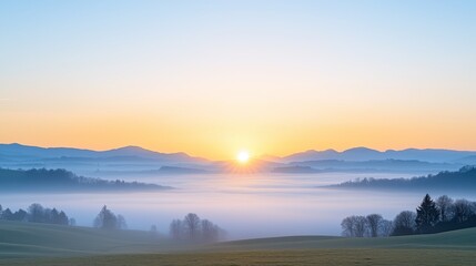 A serene sunrise over misty hills, casting warm hues across the sky, creating a tranquil and picturesque landscape.