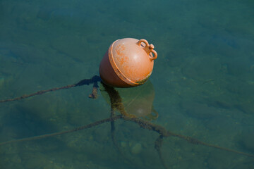 Rot / Orange Boje mit Tauen in einem Hafen (nautic sea buoy)