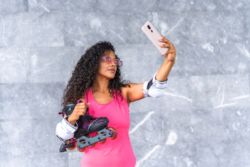 Latin woman taking selfie while carrying inline skates