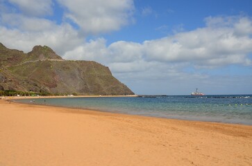 Amazing view of beach las Teresitas with yellow sand, umbrellas, longues and palm trees