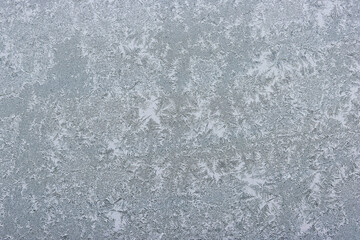 Ice crystals formed on glass in winter, creating an intricate and frosted pattern.