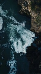 Obraz premium Aerial view of dark blue water crashing against rocky cliffs.