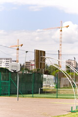 boisko sportowe na tle dźwigów budowlanych i bloków mieszkalnych