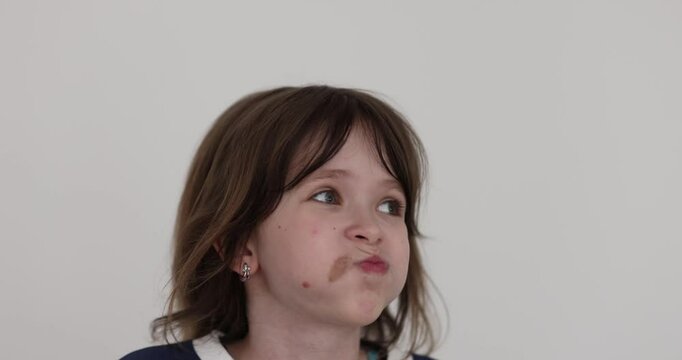 Elementary girl with dark loose hair puffs up cheeks in bewilderment slow motion. Charismatic child expresses confusion and disagreement