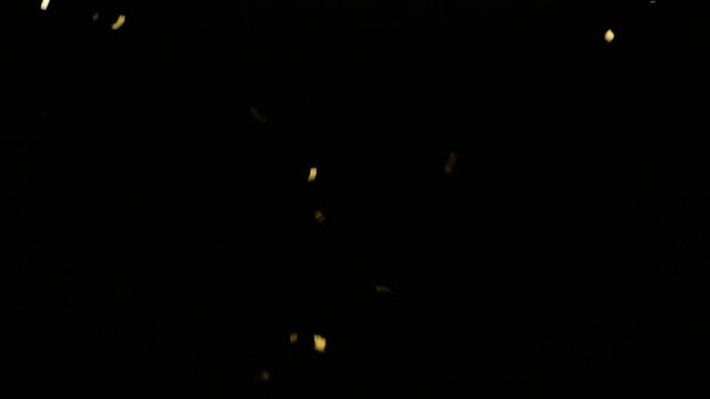 real gold confetti rain isolated on black background,  texture decoration overlay template for festive holiday celebrations