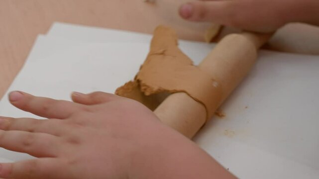 A child rolls out plasticine with a wooden rolling pin for modeling objects. Children's lessons on creating toys from plasticine. Modeling of objects in a children's school circle. Close-up