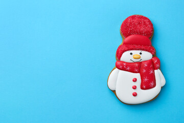 Tasty Christmas cookie in shape of snowman on light blue background, top view. Space for text