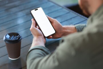 Man with paper cup using smartphone at outdoor cafe, closeup. Space for design