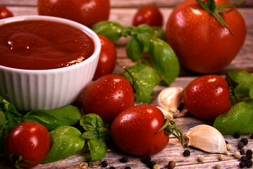 ingredients for making ketchup. ketchup in a white bowl on the table with tomatoes and basil.