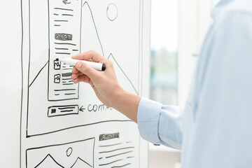Developing UI design. Man drawing website wireframe on whiteboard indoors, closeup