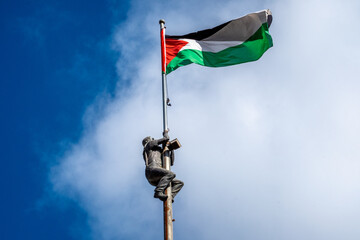 Statue of a man climbing a pole toward a Palestine flag in downtown Ramallah