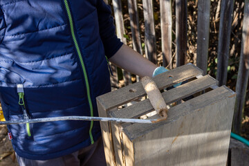 a child paints a wooden box with brushes in the garden