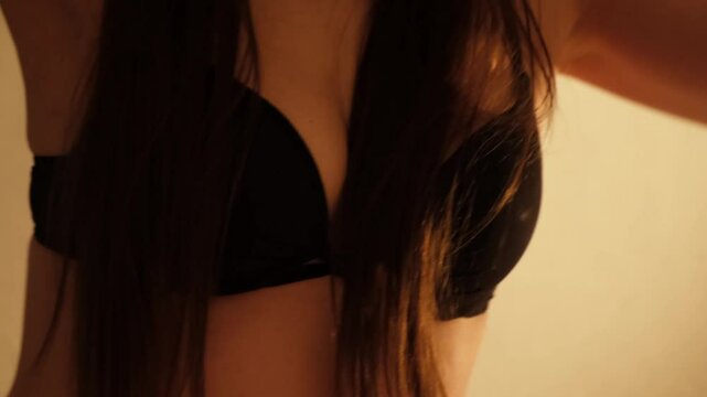Breasts of sexy girl in black bra. Young confident woman dancing erotic dance. Brunette with long hair. Concept of love and foreplay of sex. Beautiful fit body. Arousal and lust. 4K