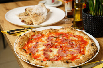 Original Italian pizza with ham, tomato sauce and cheese at a restaurant