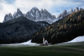 San Giovani's church in dolomites with snowy grass and mountains in the back