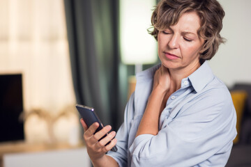 Woman holding mobile phone suffering neck pain caused by bad posture. People and health concept