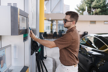 Man pay for petrol on self service gas station using his smartphone. Contactless payment. Fuel...