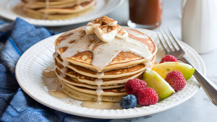 A plate of cinnamon roll pancakes with cream cheese glaze, topped with a sprinkle of cinnamon and served with a side of fresh fruit.  