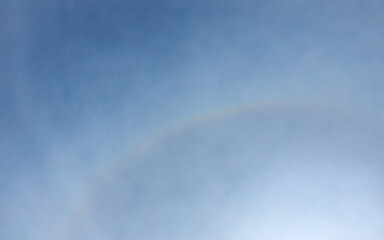 Naklejka premium Scenic sunbeams through the clouds with circular rainbow in the blue sky, Cloudscape 