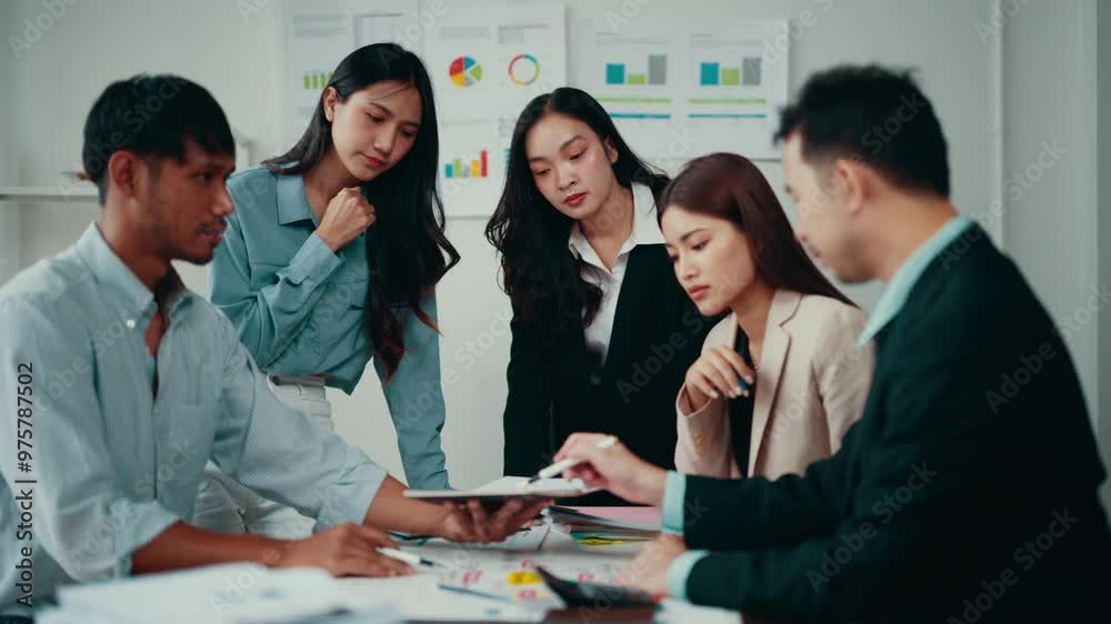 Poster Team of marketing professionals gathered around a table, engaging in a brainstorming session while reviewing financial data displayed on a tablet