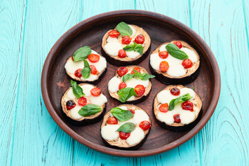 Italian mini pizza . Aubergine (eggplant ) with mozzarella cheese and basil . On rustic background